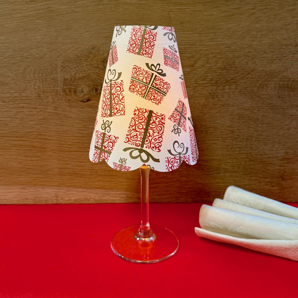 un verre à pied décoré d'un abat jour en papier motif cadeaux