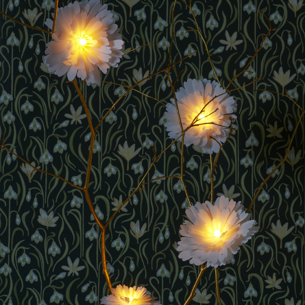 des fleurs lumineuses suspendues dans des branches 