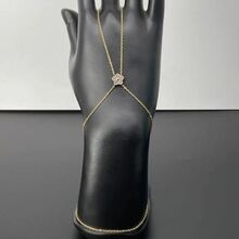 Bracelet bague fin en chaîne dorée avec un motif floral au dos de la main