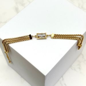 Bracelet à triple chaîne doré avec un ornement central rectangulaire serti d'un cristal