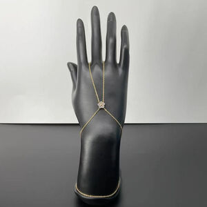 Bracelet bague fin en chaîne dorée avec un motif floral au dos de la main