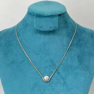 Collier doré orné d'un pendentif en perle entourée de petites pierres lumineuses